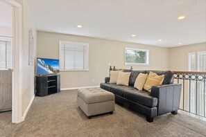 House 1 upper loft open to lower great room with sofa and TV
