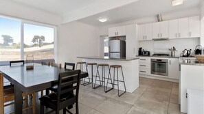 Spacious kitchen/dining equipped with generous island bench with four breakfast stools.