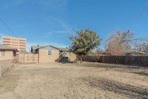 Step through the gate of the smaller courtyard and into the BIG, fully fenced backyard. This is the perfect spot for a game of catch with kids (or the dog)! 