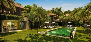 The lower level swimming pool is surrounded by lush greenery