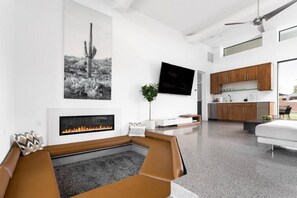 Stylish and modern living space with cozy built-in seating, a sleek fireplace, and an open kitchen—perfect for relaxing or entertaining in style!