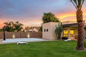 Modern desert oasis with a lush yard, basketball court, and stunning sunset views—perfect for relaxation and fun!