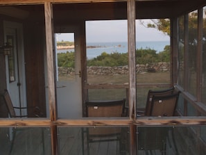 Looking through screened porch, over old stone wall to the cove.