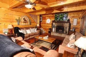 Living room with recliners, sleeper sofa, and wood burning fireplace.
