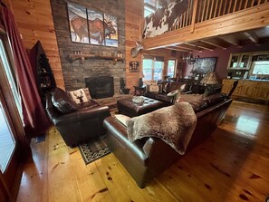 Leather seating surrounds the wood-burning stone fireplace