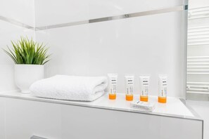 Close-up of the toiletries and towel located in the white tiled bathroom.