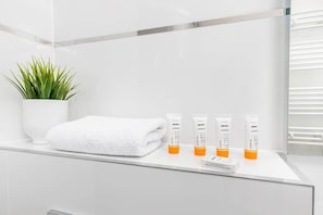 Close-up of the toiletries and towel located in the white tiled bathroom.