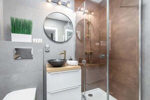 A stylish bathroom with a walk-in shower, modern fixtures, and a mix of gray and wood tones in the decor.