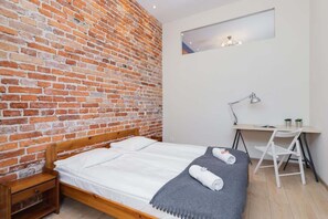 A second bedroom with a simpler design, showing a neatly made bed, a white desk, and a chair.