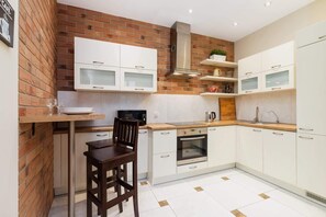 A modern kitchen with white cabinets, a wooden countertop, and a dining table with stools.