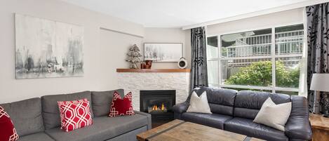 Cozy living area with gas fireplace and large windows overlooking the garden