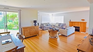 Open plan living that takes you out onto the back deck through sliding doors, looking over the green lawn and native trees that surround the property.