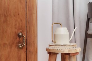 A close-up of a wooden door handle with a decorative vase and jug in the background.