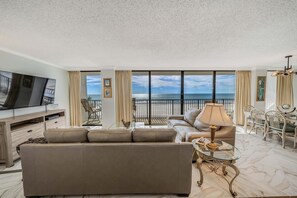 The living room offers ample, comfortable seating, large flat screen television, and expansive views of the sugar white sands and emerald green waters.