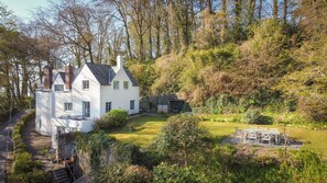 Property showing long garden and dining table on patio overlooking the beach.