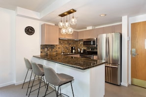 Kitchen features granite countertops and stainless steel appliances and a breakfast bar