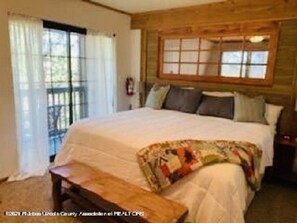 This upstairs bedroom has a small balcony with sitting area and queen bed. 