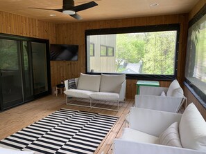 Open air porch off the great room has cozy seating, and a smart tv.