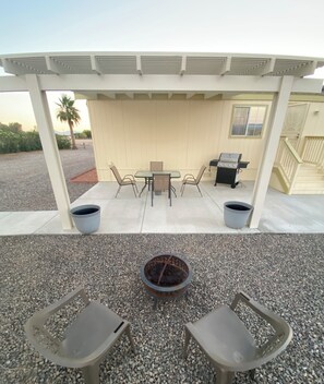 Back patio with outdoor dining table, BBQ and fire pit.