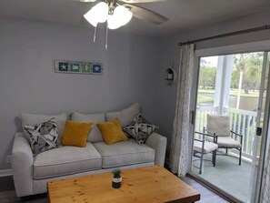 Cozy living room with sofa bed and balcony overlooking the pool