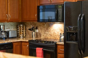 Black Appliances and Wooden Cabinets at Mauna Lani Hawai'i Vacation Rentals