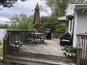 Side deck facing the water with a BBQ grill and outdoor dining.  