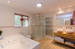 The spacious family bathroom with Jacuzzi bath and drench shower.