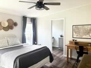 Spacious master suite with cotton sheets, blackout curtains, desk, ceiling fan