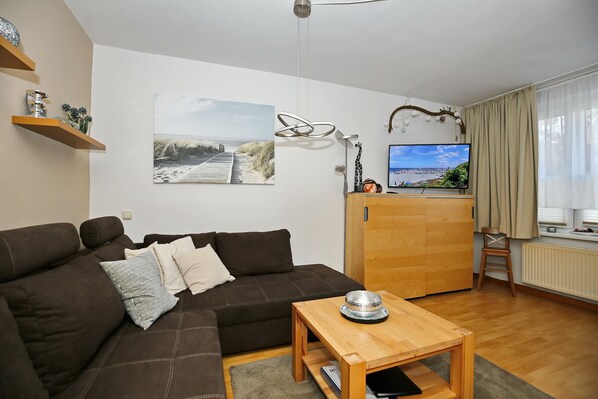 Wohnzimmer mit Schlafcouch, Sideboard und TV