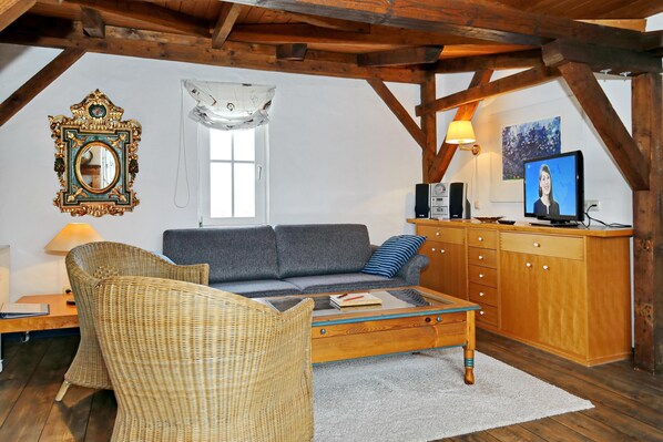 Wohnzimmer mit Schlafsofa und Korbsesseln