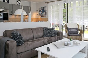 Wohnzimmer mit Schlafcouch und Korbsessel