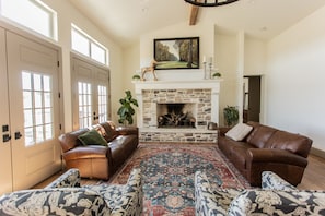 large great room with grand fireplace and doors opening to the deck