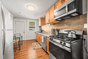 Full kitchen with eat-in area and backdoor leading to laundry and patio.