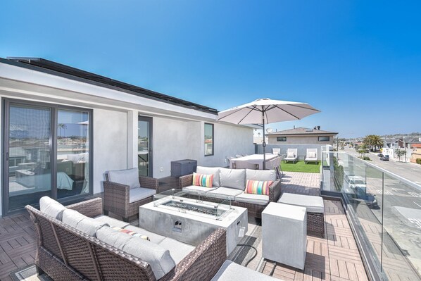Upper deck of this modern three-level vacation home. Ample seating and gas fire pit make this THE hangout spot after a day at the beach.
                