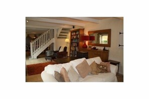 Open plan living space with 2 sofas, armchairs, TV with Netflix and reading area