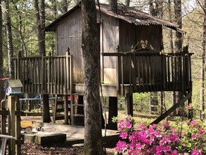 Treehouse and sandbox in the fenced back yard.