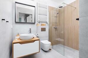 The bathroom's contemporary design includes fresh towels and a hairdryer. 