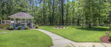 Spacious fenced in backyard with firepit, gazebo, and outdoor games