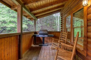 Gas grill on back deck with four rocking chairs.