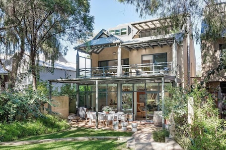 The lush backyard flows seamlessly to the alfresco dining area, creating a peaceful, private retreat.