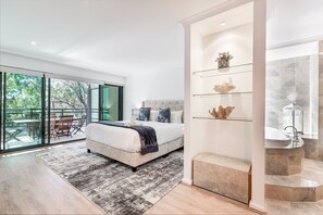 Wake up to dappled sunlight through the trees in the stunning primary suite, featuring a king-sized bed, a private spa bath, and direct balcony access.