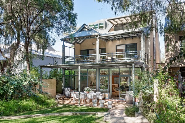 The lush backyard flows seamlessly to the alfresco dining area, creating a peaceful, private retreat.