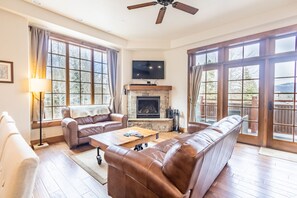 Living area offering ample seating, large wall mounted flat screen TV, a gas fireplace, and great views.