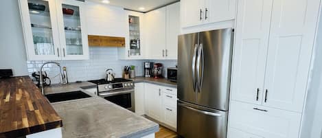Well eqiupped kitchen with stainless appliances and concrete countertops. 