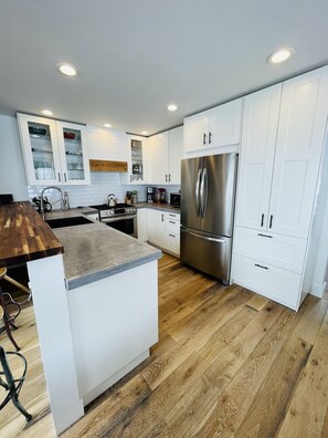 Well eqiupped kitchen with stainless appliances and concrete countertops. 