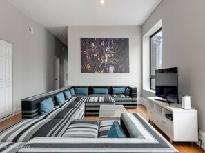 Another view of the living room with huge couch and prominent windows overlooking scenic and historic Wells Street.