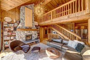 Natural light floods the open concept living area featuring vaulted ceilings and a wood burning fireplace