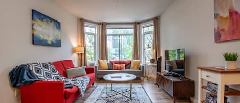 Spacious Living Room with Bay Windows, a 50" Smart TV and Sofa Bed.