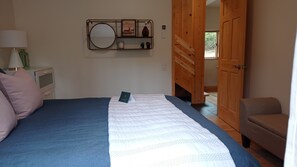 This bedroom has a queen size bed, dresser, sitting area, and clothing rack.