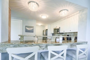 The renovated kitchen features granite counters, stool seating and stainless steel appliances.